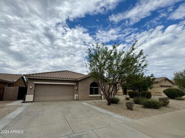 view of front of house featuring a tiled roof, concrete driveway, an attached garage, and stucco siding