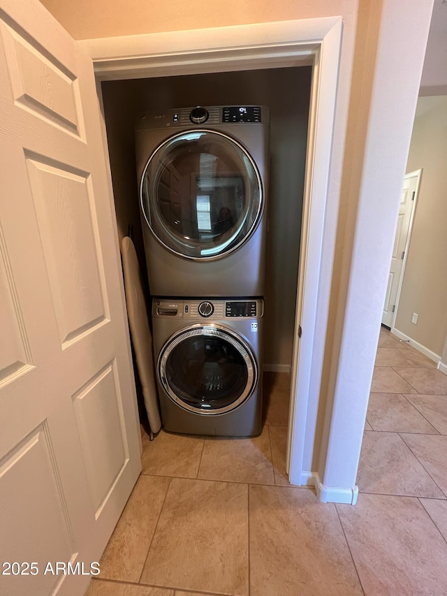 laundry room with light tile patterned floors and stacked washer / dryer