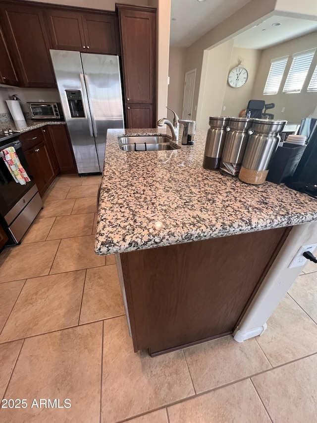 kitchen featuring light stone counters, appliances with stainless steel finishes, light tile patterned floors, and sink