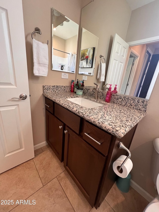 bathroom with toilet, vanity, and tile patterned flooring