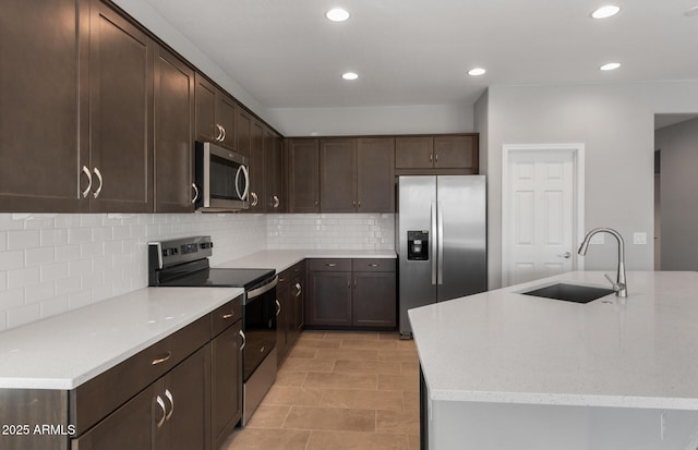 kitchen featuring tasteful backsplash, stainless steel appliances, a kitchen island with sink, and sink