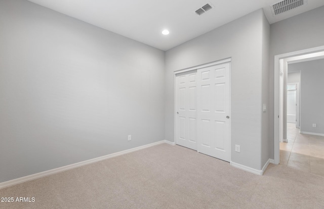 unfurnished bedroom with light colored carpet and a closet