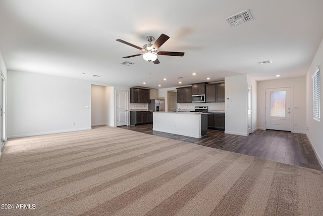 kitchen with dark hardwood / wood-style floors, a center island with sink, appliances with stainless steel finishes, ceiling fan, and dark brown cabinetry