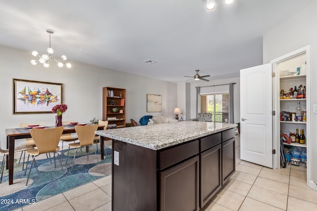 kitchen featuring dark brown cabinetry, ceiling fan with notable chandelier, light tile patterned floors, and decorative light fixtures