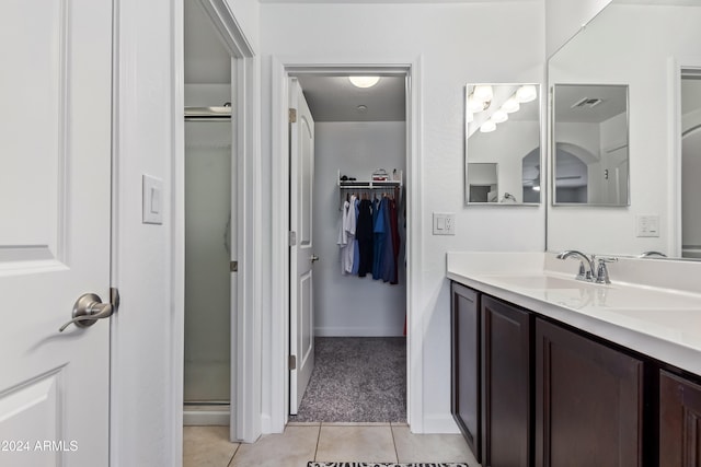 bathroom featuring tile patterned flooring, vanity, and a shower with door