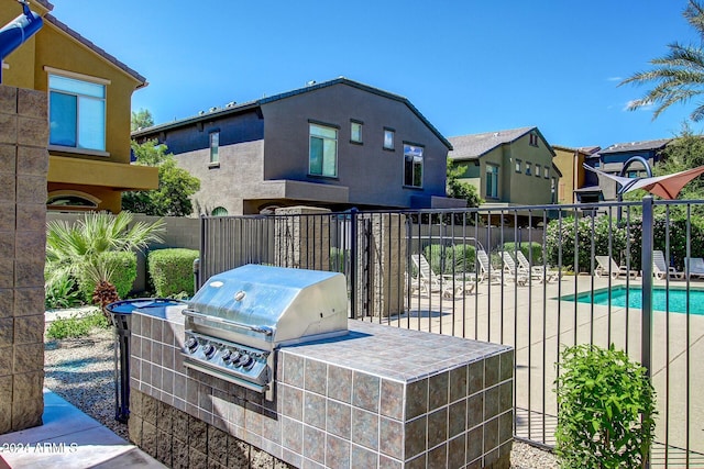 view of patio / terrace with a fenced in pool, grilling area, and exterior kitchen