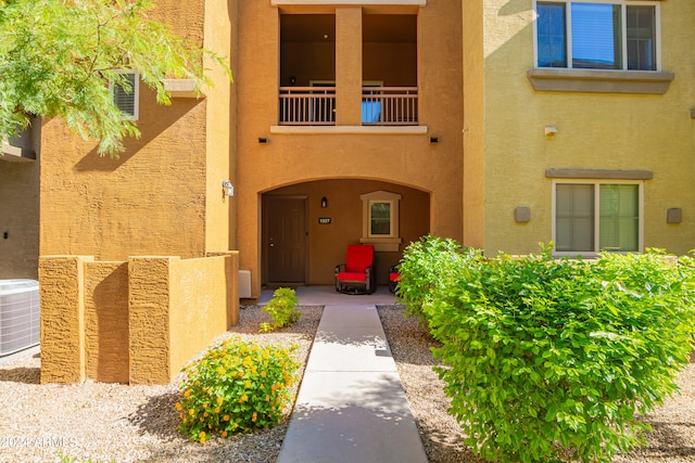 view of exterior entry with cooling unit and a balcony