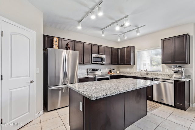 kitchen with light tile patterned flooring, a kitchen island, appliances with stainless steel finishes, track lighting, and dark brown cabinetry