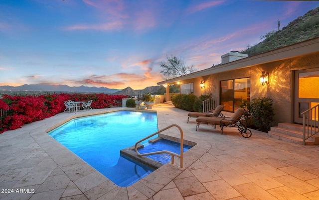 pool at dusk with a mountain view and a patio