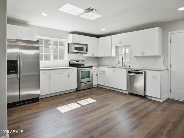 kitchen with stainless steel appliances, dark hardwood / wood-style flooring, sink, and white cabinets