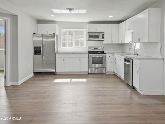 kitchen with white cabinetry, stainless steel appliances, light hardwood / wood-style floors, and sink