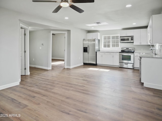 kitchen with light hardwood / wood-style flooring, appliances with stainless steel finishes, ceiling fan, light stone countertops, and white cabinets