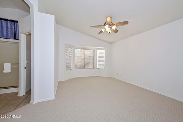 unfurnished bedroom with ceiling fan, vaulted ceiling, and light carpet