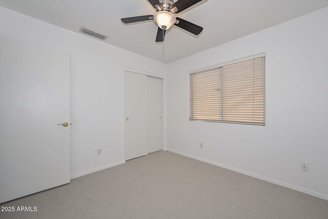 unfurnished bedroom with light carpet, a closet, and ceiling fan