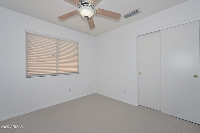 unfurnished bedroom featuring light colored carpet, a closet, and ceiling fan