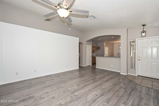 unfurnished living room with hardwood / wood-style floors, vaulted ceiling, sink, and ceiling fan