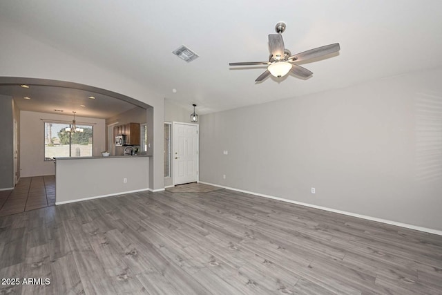 unfurnished living room with hardwood / wood-style flooring and ceiling fan with notable chandelier