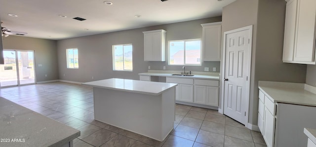 kitchen featuring light tile floors, a kitchen island, ceiling fan, white cabinets, and sink