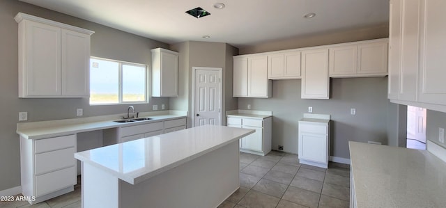 kitchen with a kitchen island, light tile flooring, white cabinetry, and sink