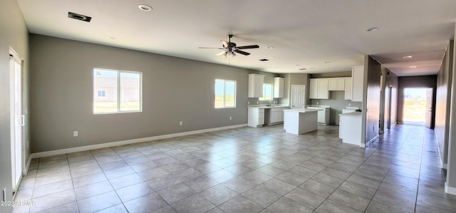 unfurnished living room featuring ceiling fan, sink, and light tile floors