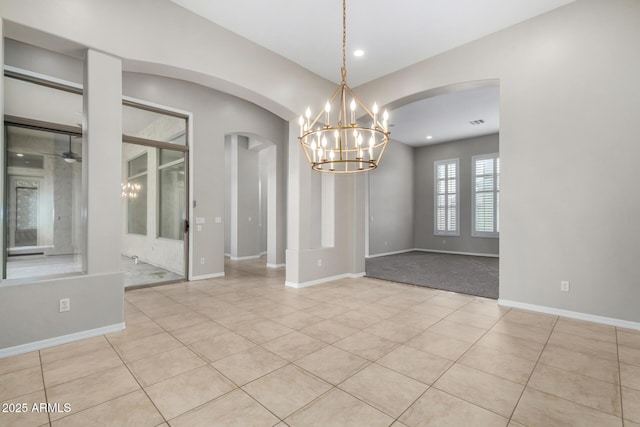 tiled spare room featuring ceiling fan with notable chandelier