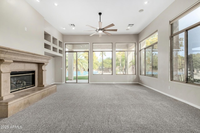 unfurnished living room featuring ceiling fan, a fireplace, carpet floors, and a wealth of natural light