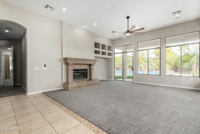 unfurnished living room with light tile patterned flooring, a high end fireplace, and ceiling fan