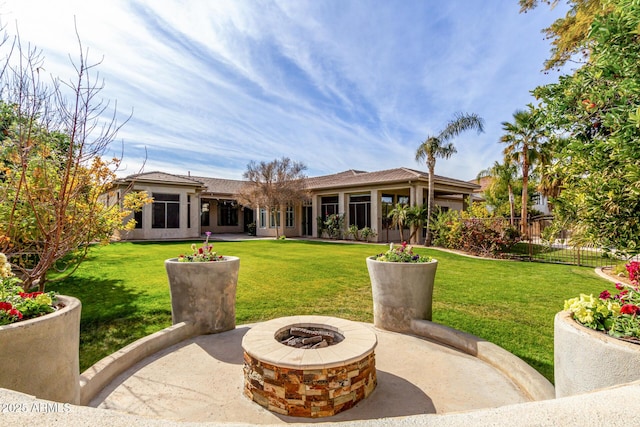 back of house with a fire pit and a lawn