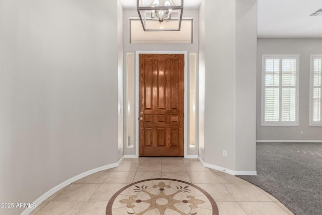 foyer with light colored carpet and a notable chandelier