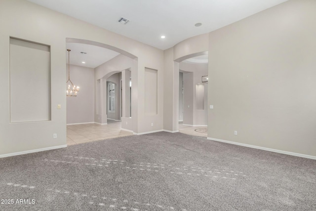 empty room with light colored carpet and an inviting chandelier