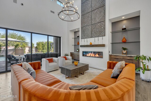 2652 E Pelican Ct, Gilbert, AZ 85297 - living area with a towering ceiling, a glass covered fireplace, a chandelier, built in features, and wood finished floors