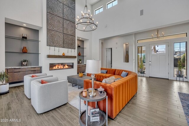 2652 E Pelican Ct, Gilbert, AZ 85297 - living room with a chandelier, a towering ceiling, wood finished floors, a glass covered fireplace, and built in shelves