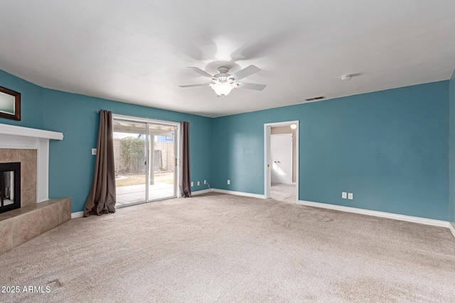 unfurnished living room with a tiled fireplace, light carpet, and ceiling fan