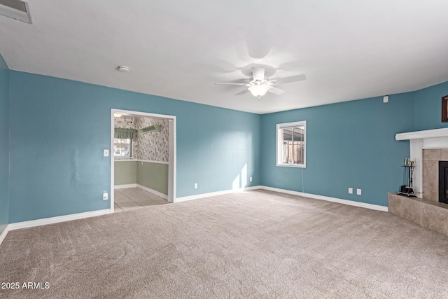 unfurnished living room featuring ceiling fan, plenty of natural light, a tiled fireplace, and light carpet