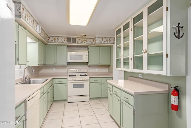 kitchen featuring white appliances, sink, green cabinets, and light tile patterned floors