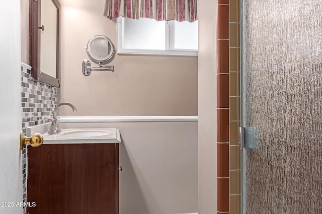 bathroom with vanity, backsplash, and a shower with door