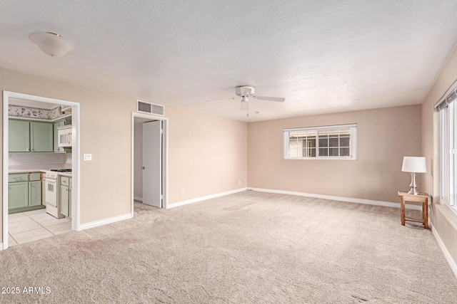 unfurnished bedroom with light colored carpet, ensuite bathroom, multiple windows, and a textured ceiling