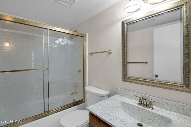 bathroom with combined bath / shower with glass door, visible vents, toilet, and vanity