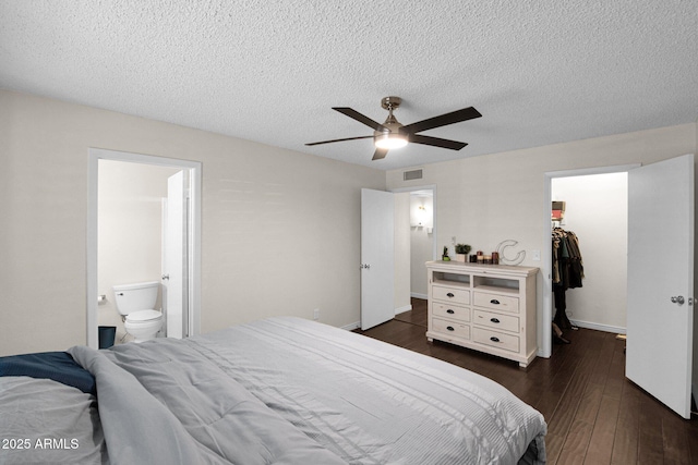 bedroom featuring visible vents, dark wood finished floors, a spacious closet, a closet, and connected bathroom