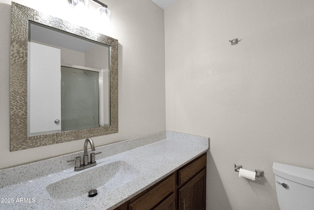 bathroom featuring toilet, a stall shower, and vanity