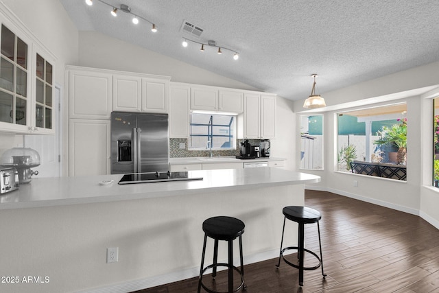 kitchen with lofted ceiling, visible vents, stainless steel refrigerator with ice dispenser, and a sink