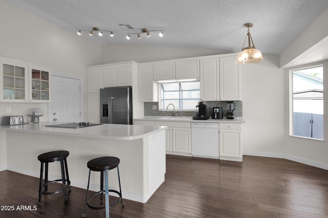 kitchen with black electric stovetop, dishwasher, lofted ceiling, stainless steel fridge, and a sink