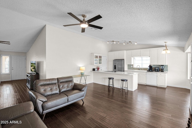 living area featuring dark wood-style floors, visible vents, ceiling fan, vaulted ceiling, and a textured ceiling