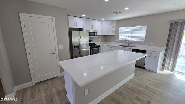 kitchen with light wood-style flooring, plenty of natural light, stainless steel appliances, open shelves, and a sink