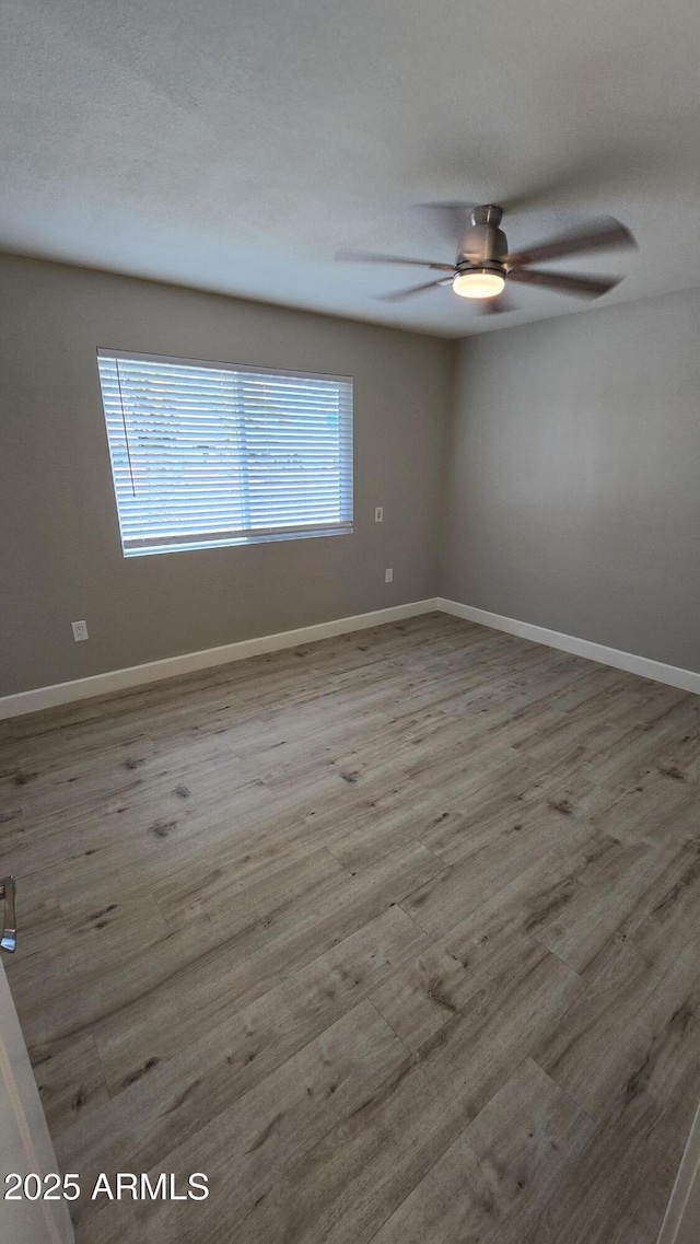 unfurnished room featuring wood finished floors, a ceiling fan, and baseboards
