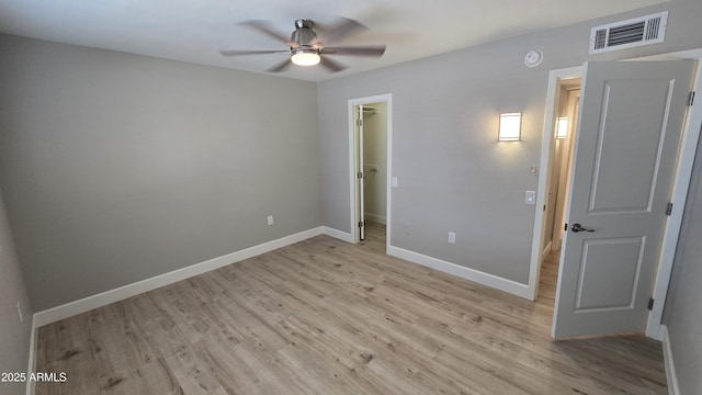 unfurnished bedroom with a spacious closet, a closet, light wood finished floors, baseboards, and visible vents