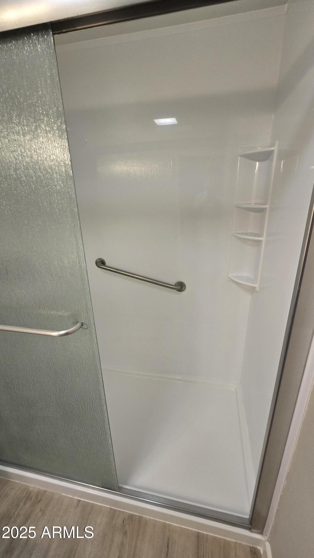 bathroom featuring a shower stall and wood finished floors