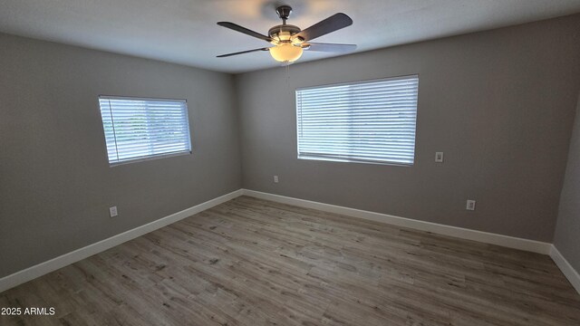empty room with ceiling fan, wood finished floors, and baseboards