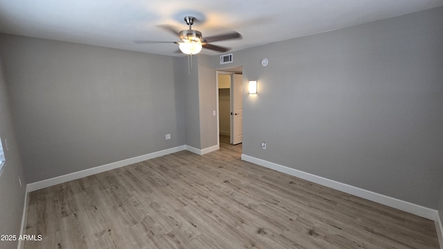 empty room featuring light wood-type flooring, visible vents, a ceiling fan, and baseboards