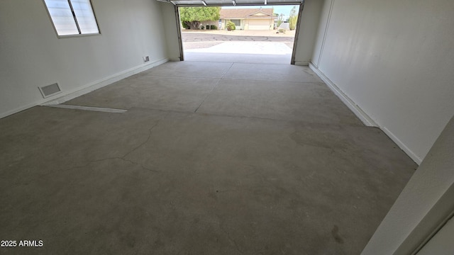 hall with concrete floors, visible vents, and baseboards